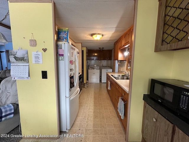 kitchen featuring independent washer and dryer, decorative backsplash, sink, and white refrigerator