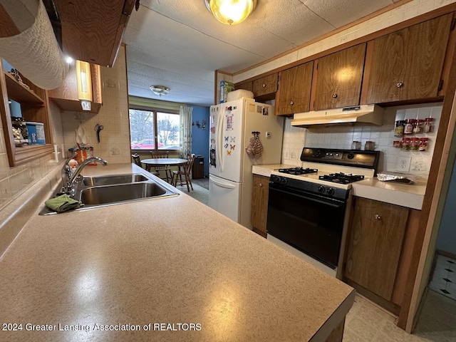 kitchen featuring range, backsplash, white fridge, and sink