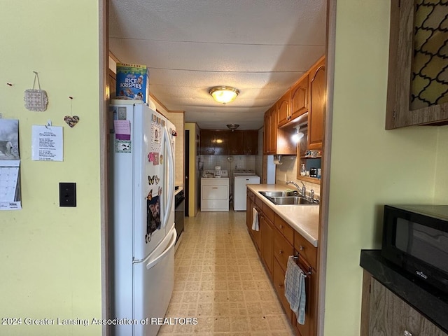 kitchen featuring washer and clothes dryer, sink, and white refrigerator