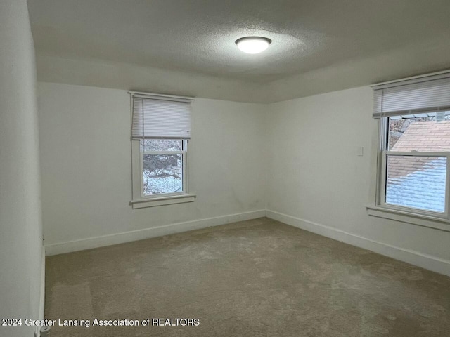 carpeted empty room featuring a textured ceiling