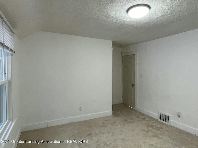 carpeted spare room featuring lofted ceiling and a textured ceiling