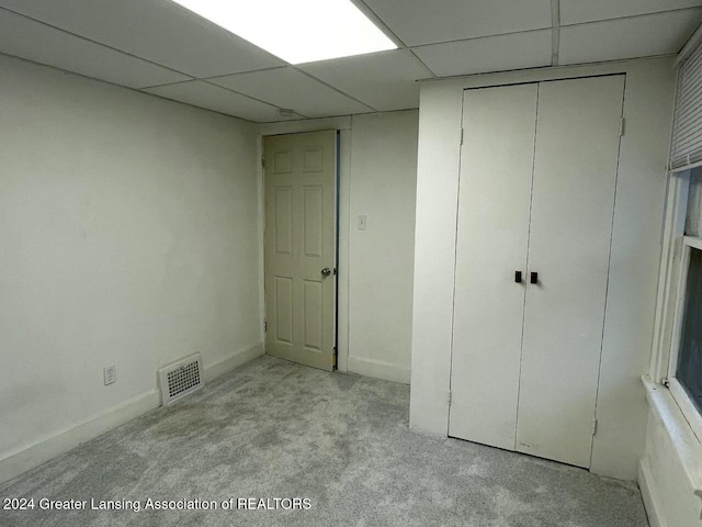 unfurnished bedroom with light carpet and a drop ceiling