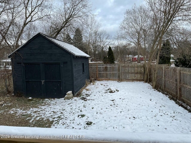 snowy yard featuring a storage unit