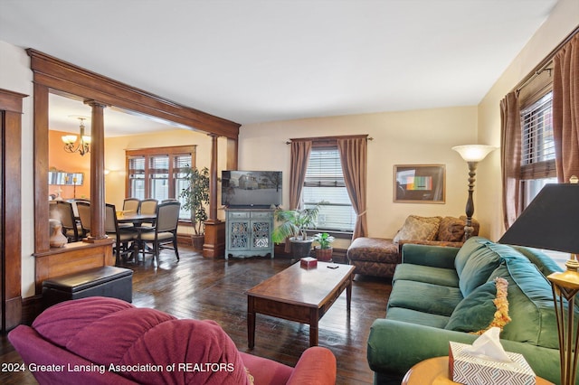 living room featuring decorative columns, dark hardwood / wood-style floors, and a notable chandelier