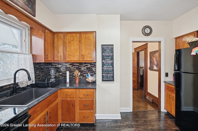 kitchen featuring tasteful backsplash, black refrigerator, and sink