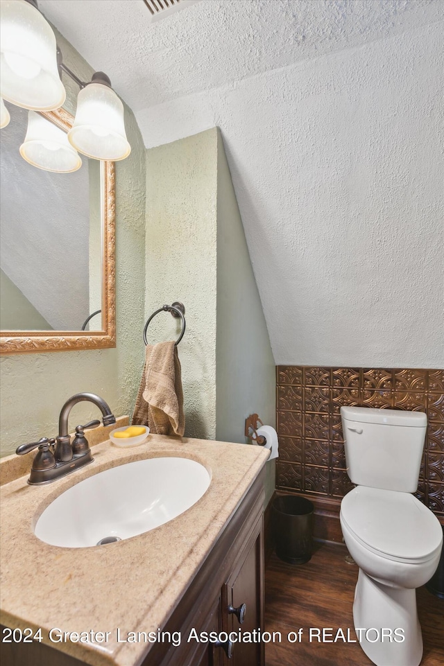 bathroom with vanity, lofted ceiling, toilet, a textured ceiling, and wood-type flooring