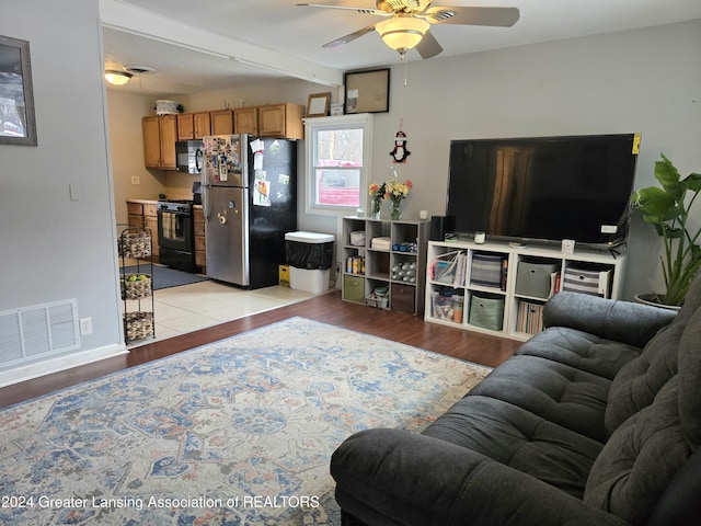 living room with beam ceiling, light hardwood / wood-style floors, and ceiling fan