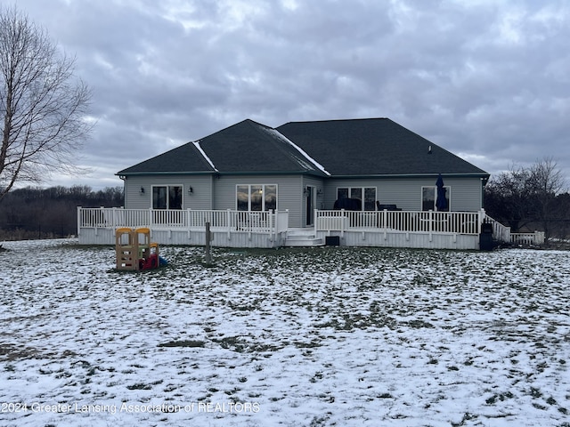 snow covered back of property with a wooden deck