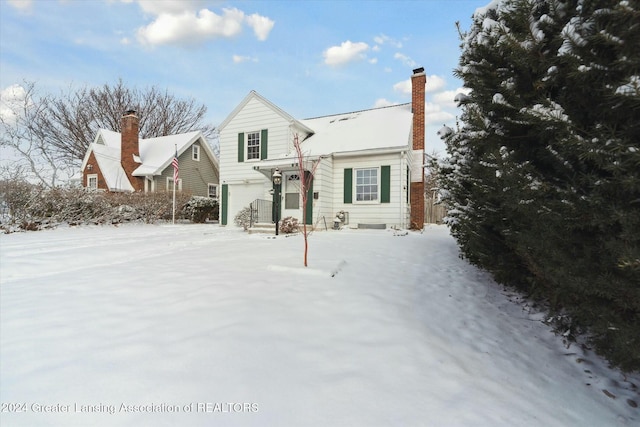 snow covered back of property with a garage