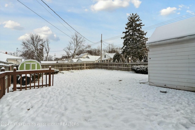 snowy yard with a deck and a storage unit