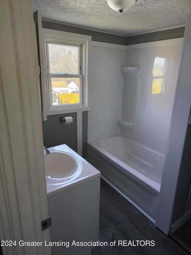 bathroom featuring bathing tub / shower combination, vanity, a textured ceiling, and hardwood / wood-style flooring