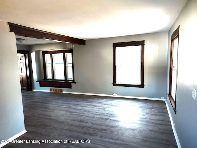 spare room with beamed ceiling and dark wood-type flooring