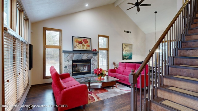 living room with a stone fireplace, high vaulted ceiling, beamed ceiling, ceiling fan, and dark wood-type flooring