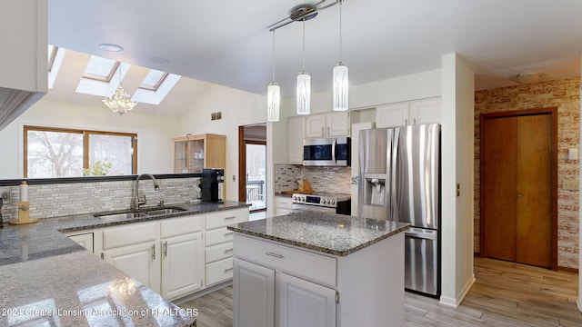 kitchen with appliances with stainless steel finishes, a center island, sink, and white cabinets