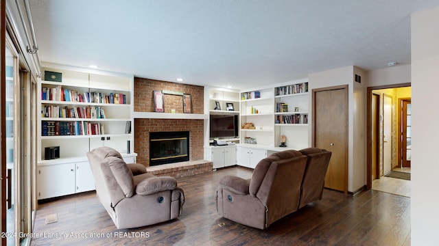 living room featuring dark wood-type flooring, a fireplace, and built in shelves