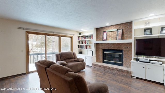 living room with built in features, dark hardwood / wood-style floors, a textured ceiling, and a fireplace