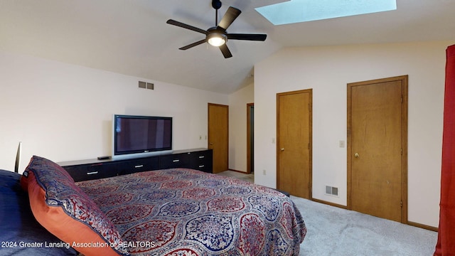 carpeted bedroom with ceiling fan and vaulted ceiling with skylight