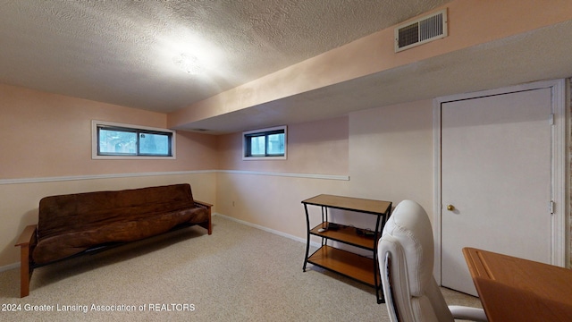 living area featuring light carpet and a textured ceiling