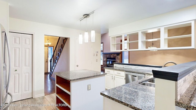 kitchen featuring white cabinetry, dark stone countertops, stainless steel appliances, a kitchen island, and decorative light fixtures