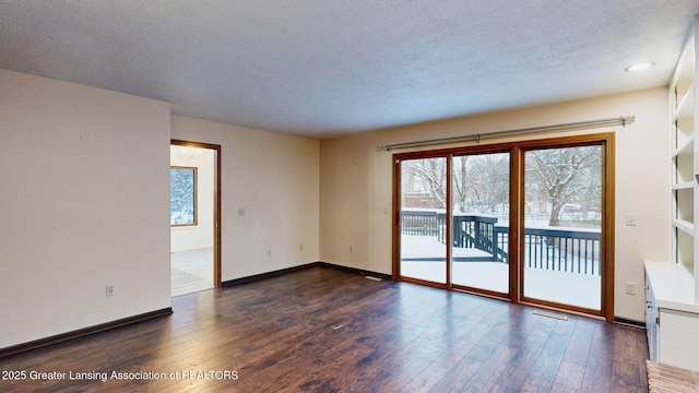 spare room featuring dark hardwood / wood-style flooring and a textured ceiling