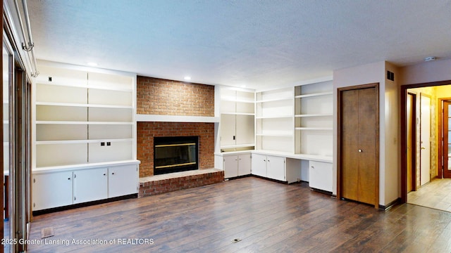 unfurnished living room with a fireplace, dark hardwood / wood-style flooring, and a textured ceiling