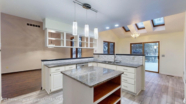 kitchen with a center island, dark stone counters, kitchen peninsula, and sink