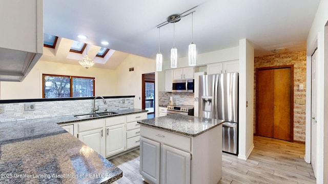 kitchen featuring stainless steel appliances, a center island, sink, and white cabinets