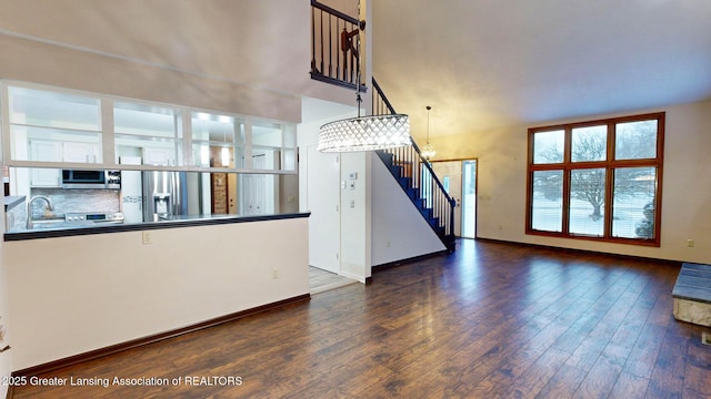 unfurnished living room featuring dark hardwood / wood-style floors, sink, and a notable chandelier