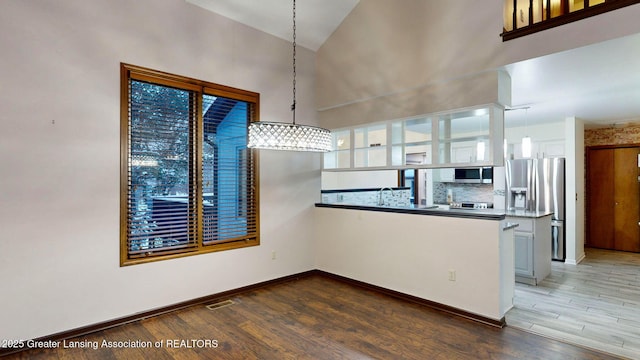 kitchen with pendant lighting, stainless steel appliances, wood-type flooring, white cabinets, and decorative backsplash