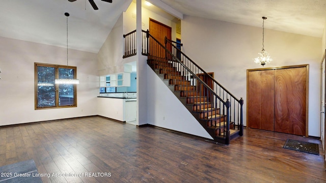 foyer with ceiling fan with notable chandelier, dark hardwood / wood-style flooring, and high vaulted ceiling