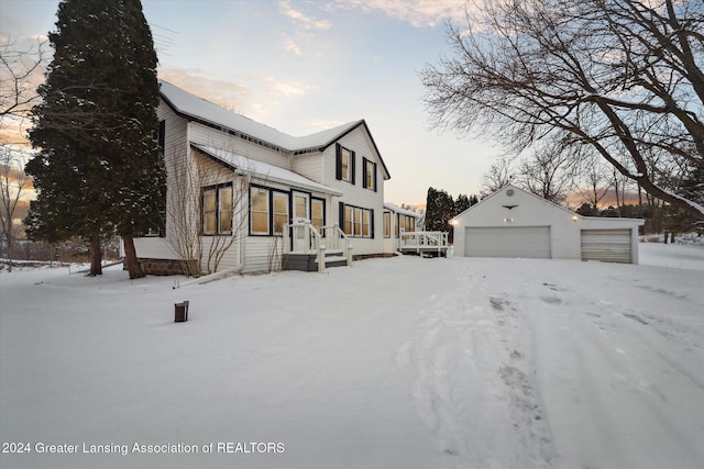 view of snowy exterior featuring a garage and an outdoor structure