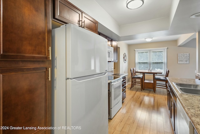 kitchen featuring white appliances, sink, and light hardwood / wood-style flooring