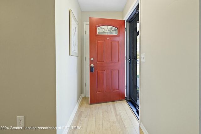 doorway to outside with light hardwood / wood-style floors and vaulted ceiling