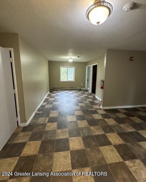 spare room with a textured ceiling and a baseboard heating unit