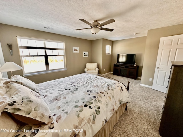 carpeted bedroom with ceiling fan and a textured ceiling