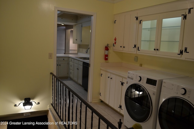 clothes washing area featuring light tile patterned floors, sink, separate washer and dryer, and cabinets