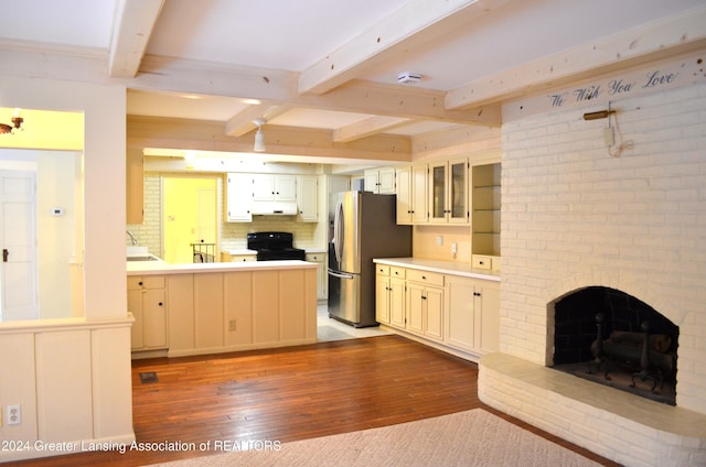 kitchen featuring tasteful backsplash, a fireplace, hardwood / wood-style flooring, black range oven, and stainless steel fridge with ice dispenser