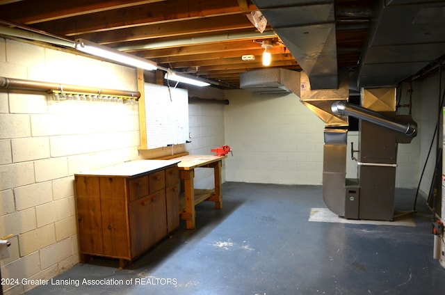 basement featuring heating unit and a workshop area