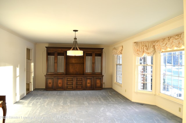 unfurnished dining area featuring ornamental molding and dark carpet