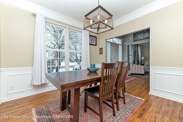 dining space with an inviting chandelier, ornamental molding, and dark hardwood / wood-style floors