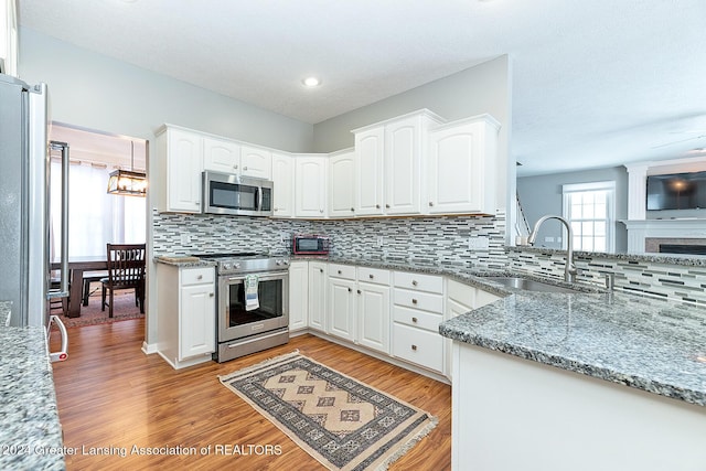 kitchen featuring decorative backsplash, sink, appliances with stainless steel finishes, white cabinets, and light stone counters