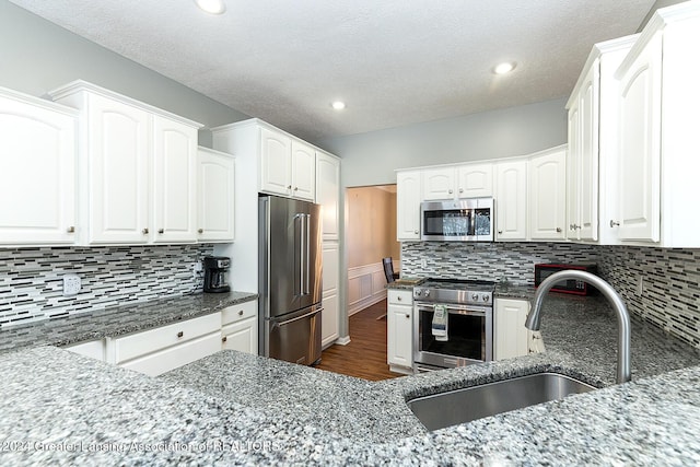 kitchen with sink, white cabinetry, dark stone counters, and high end appliances