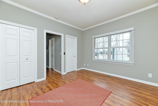 unfurnished bedroom with a closet, ornamental molding, and hardwood / wood-style floors