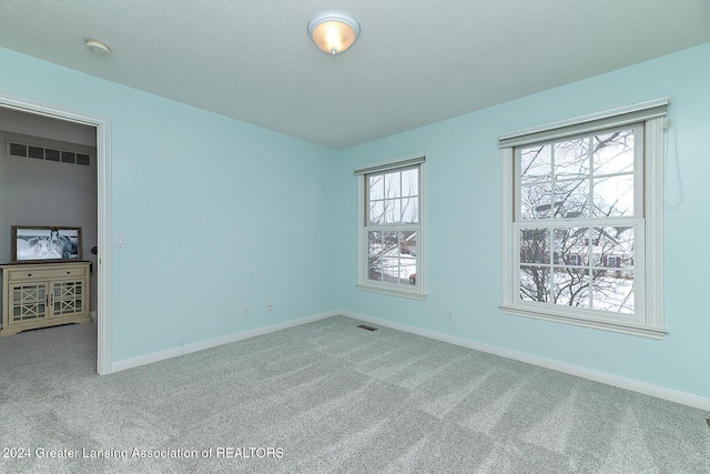 carpeted empty room with a textured ceiling