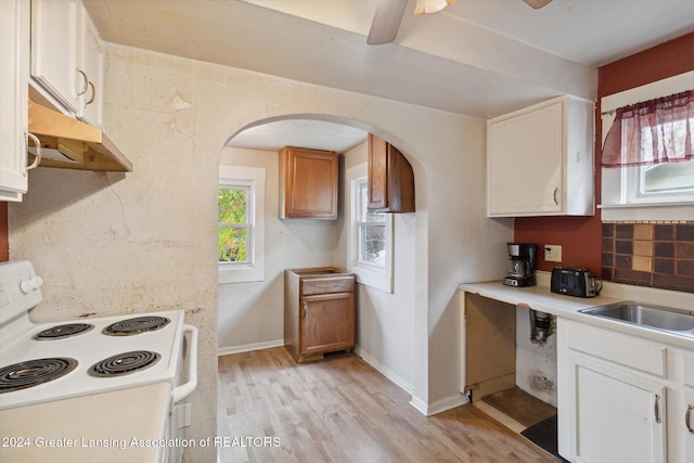 kitchen with light wood-type flooring, backsplash, sink, white range with electric cooktop, and white cabinetry