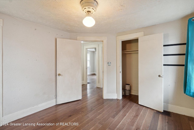 unfurnished bedroom with a closet, a textured ceiling, and hardwood / wood-style flooring