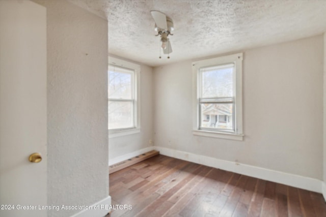 spare room with plenty of natural light, hardwood / wood-style floors, and a textured ceiling