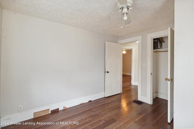 unfurnished bedroom with a textured ceiling, a closet, ceiling fan, and dark wood-type flooring