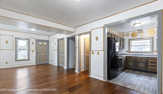 interior space with electric range, sink, dark wood-type flooring, black fridge, and a textured ceiling