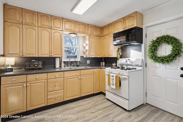 kitchen featuring white gas stove, sink, decorative backsplash, light brown cabinetry, and light wood-type flooring